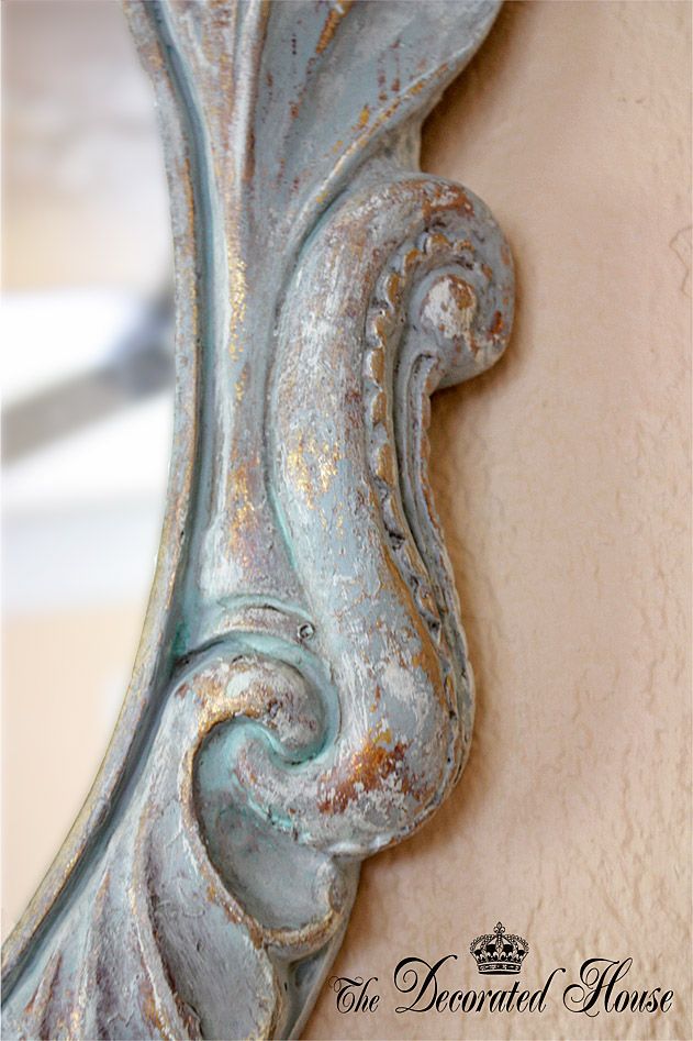 an ornate blue mirror hanging on the wall next to a stucco wall with peeling paint