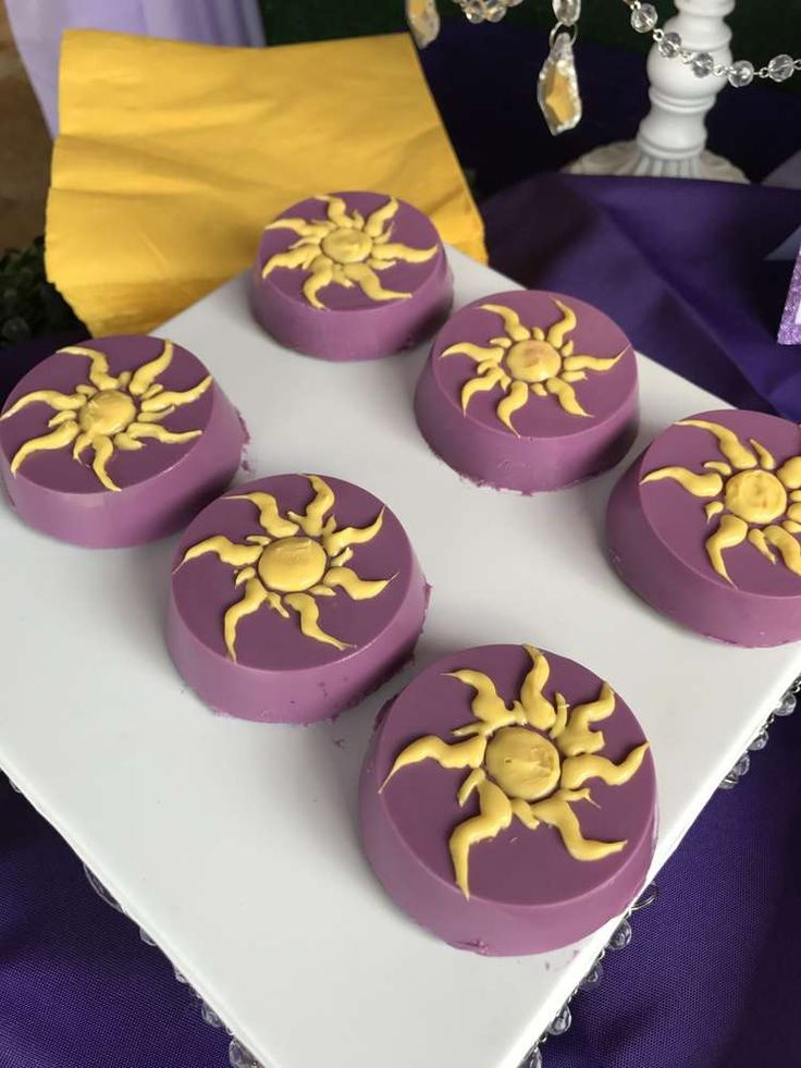 purple and yellow decorated cakes sitting on top of a table