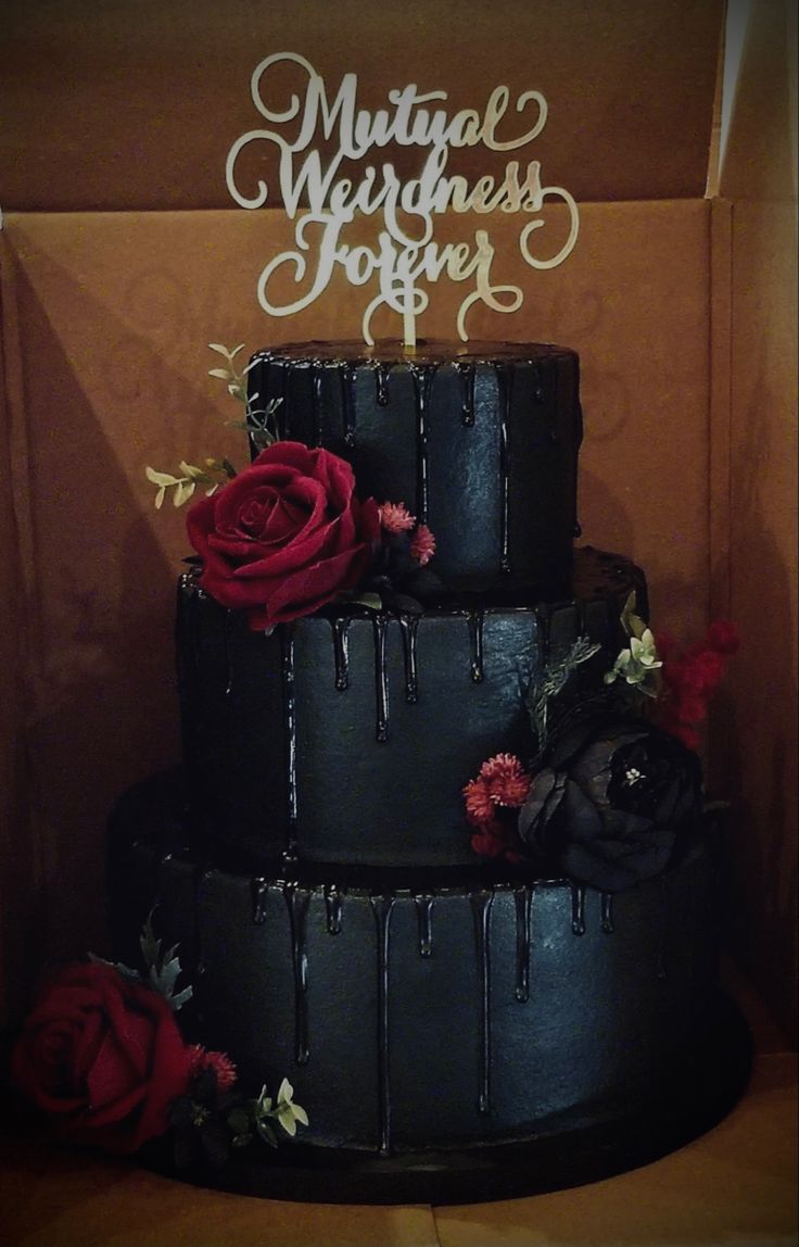 a three tiered black cake with red roses on top and the words marriage together