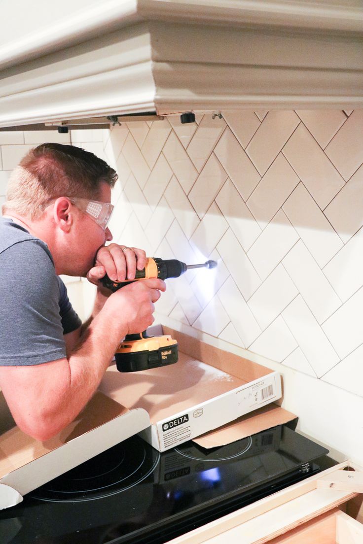 a man using a drill to fix a stove