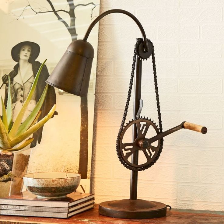 a table with a lamp and some books on it next to a plant in a vase