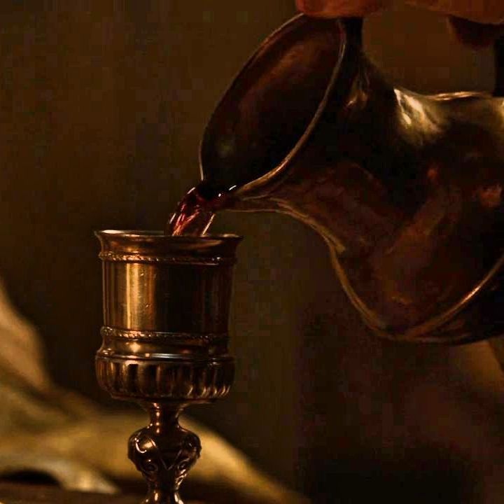 a person pouring red wine into a cup