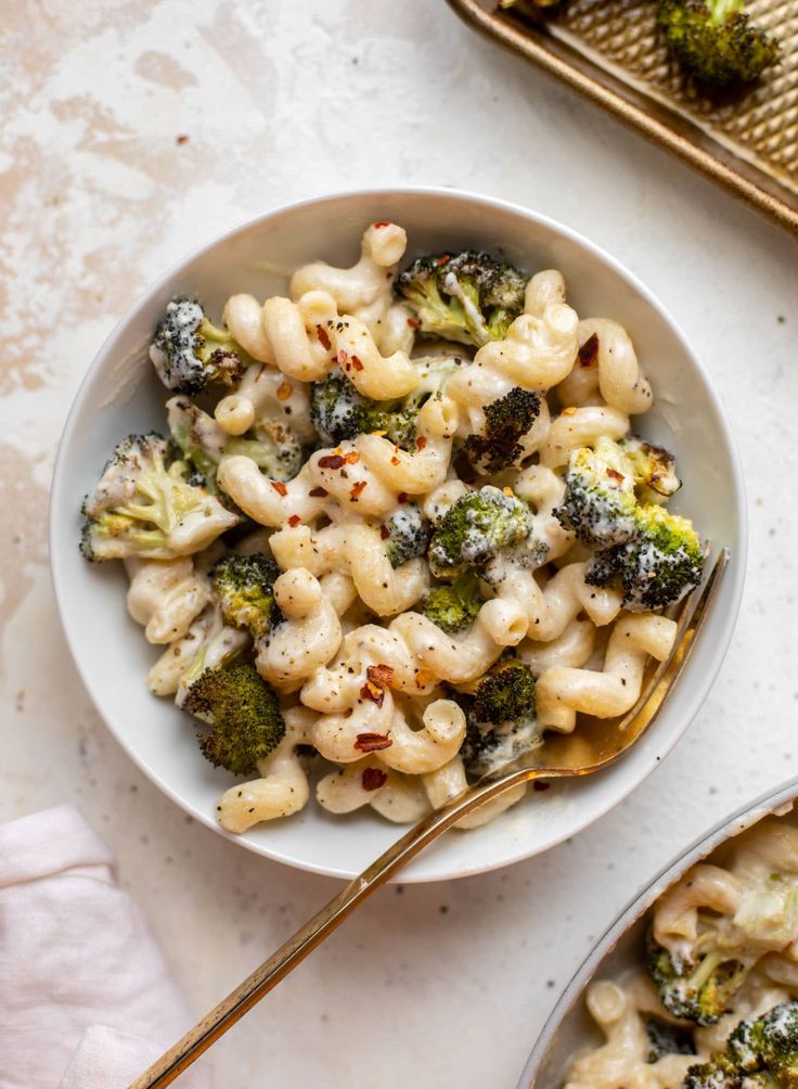 a bowl filled with macaroni and broccoli on top of a table