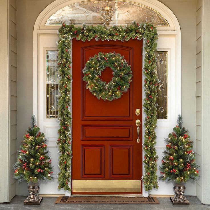 a red door decorated with christmas wreaths and garland