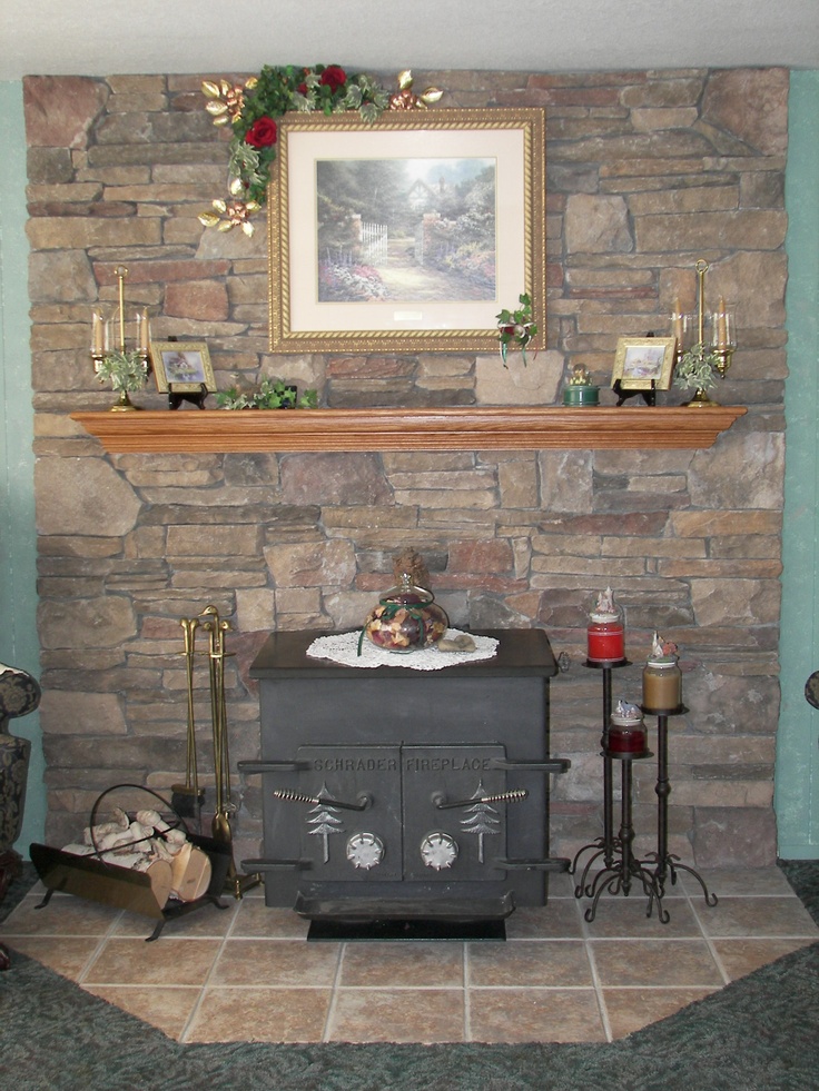 an old fashioned stove in front of a stone wall with a painting on it's mantle