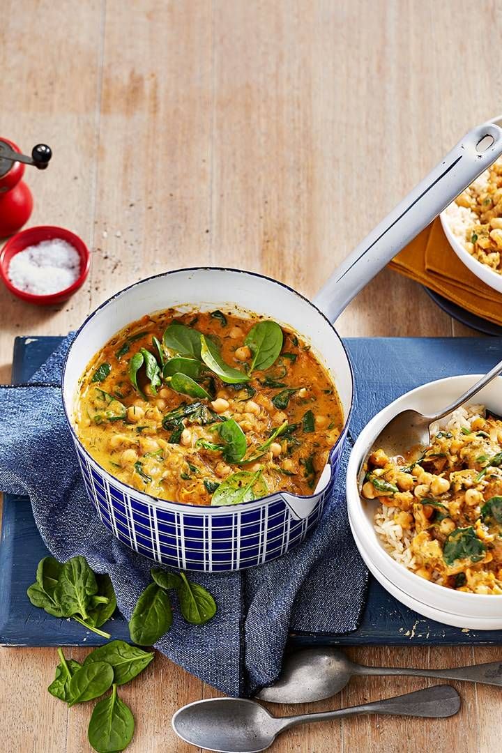 two bowls filled with food sitting on top of a blue cloth next to spoons