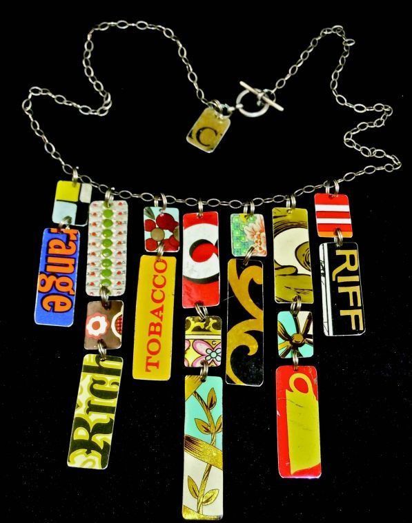 a necklace made out of different types of tags on a black cloth covered tablecloth