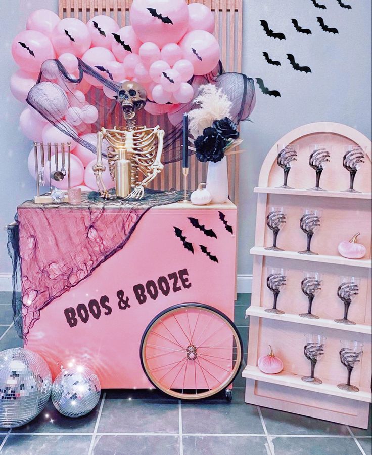 a pink cart with balloons in the shape of bats and bones on it next to other items