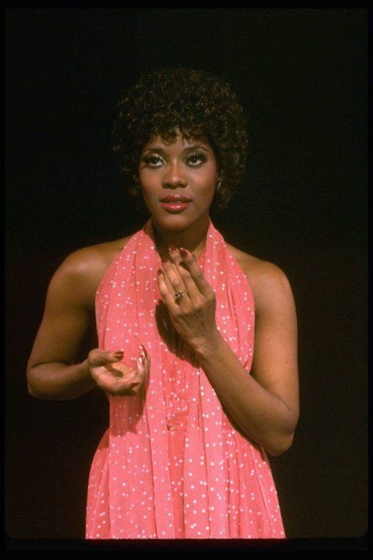 a woman in a pink dress with her hands together and an apple on the other hand