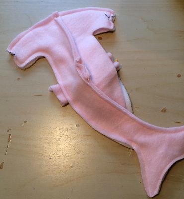 a pink stuffed animal laying on top of a wooden table next to a piece of cloth