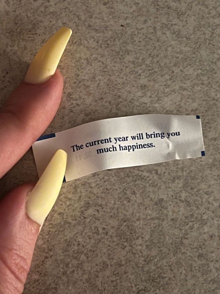 a person's hand holding a piece of paper that says the current year will bring you much happiness