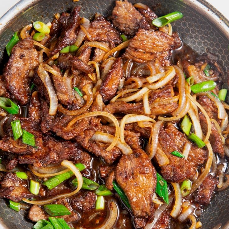 meat and onions are being cooked in a wok