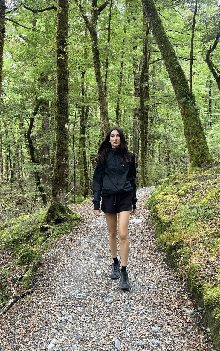 a woman walking down a trail in the woods