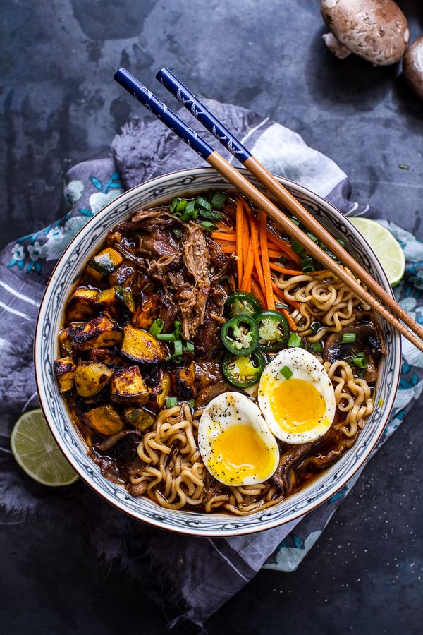 a bowl filled with noodles, eggs and vegetables next to chopsticks on the side