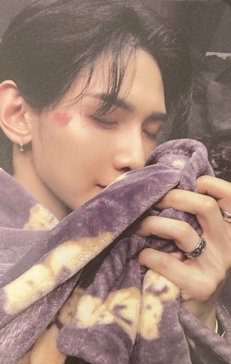 a young man with black hair and piercings is wrapped up in a purple blanket