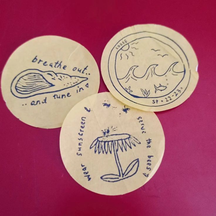 three circular stickers with designs on them sitting on a table top next to each other