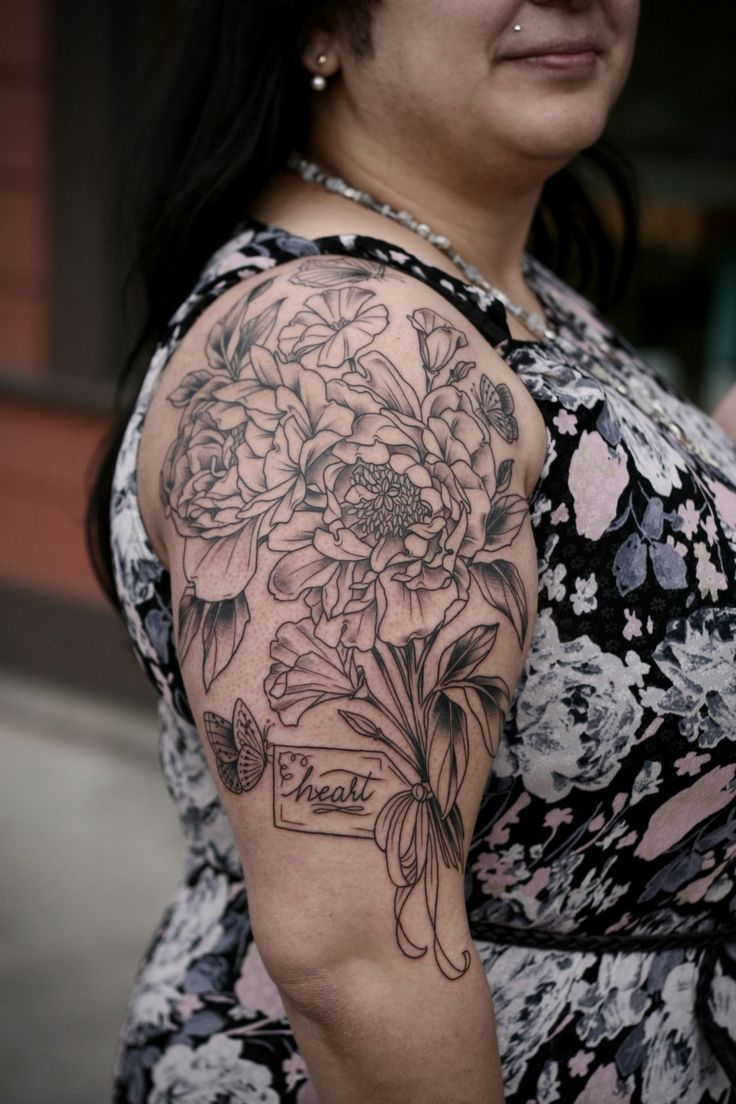 a woman with a tattoo on her arm and flowers in the middle of her arm