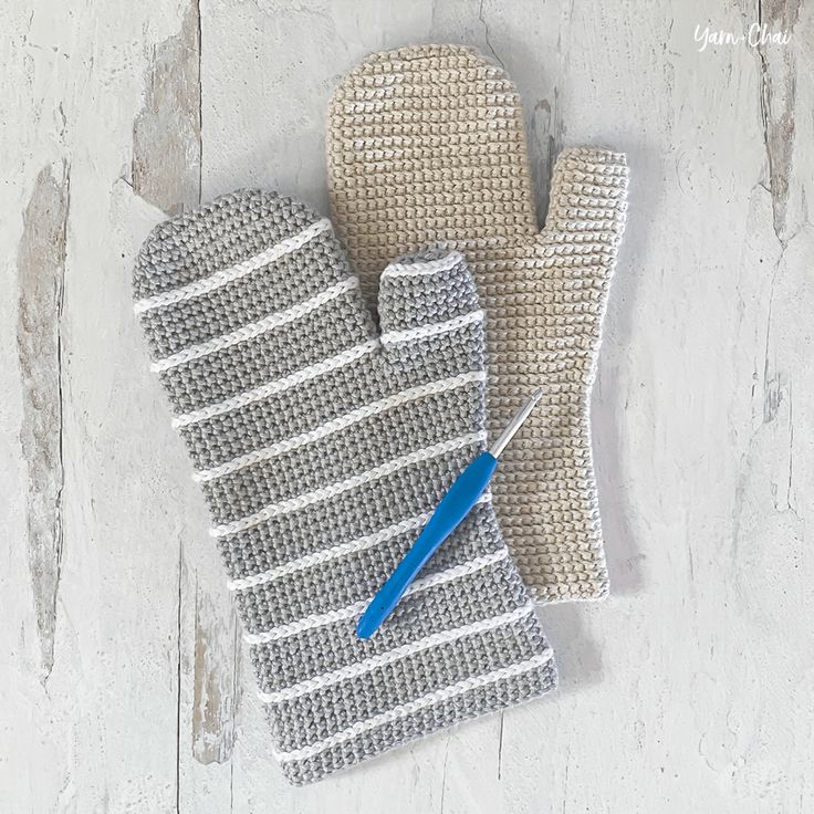 an oven mitt and glove sitting on top of a wooden table next to a blue handled spatula