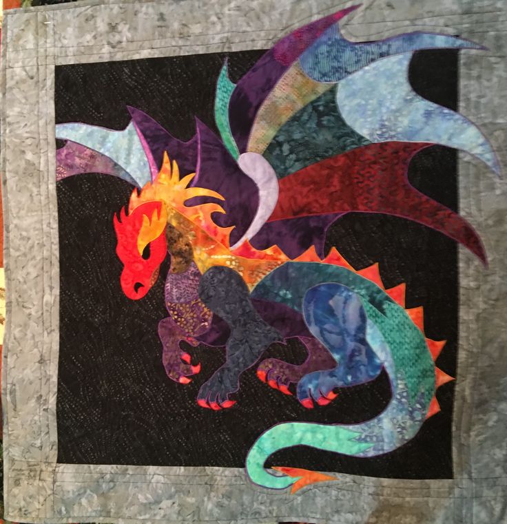 a quilted wall hanging with an image of a colorful dragon on it's side