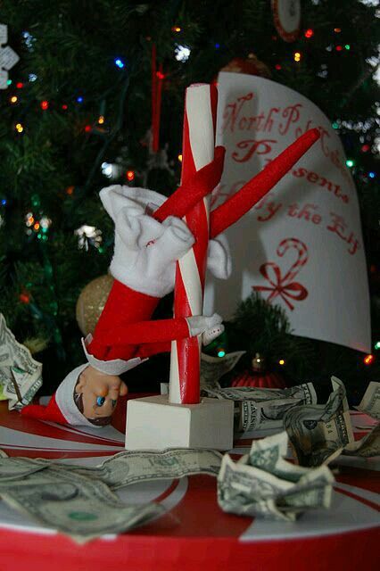 the elf is hanging upside down on the table with money in front of his face