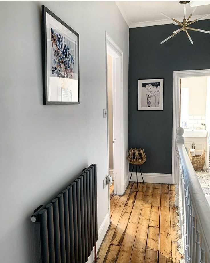 a room with blue walls and wood flooring in the hallway, along with a radiator