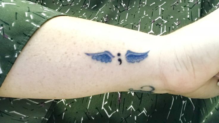 a woman's arm with an angel wing tattoo on the left side of her arm