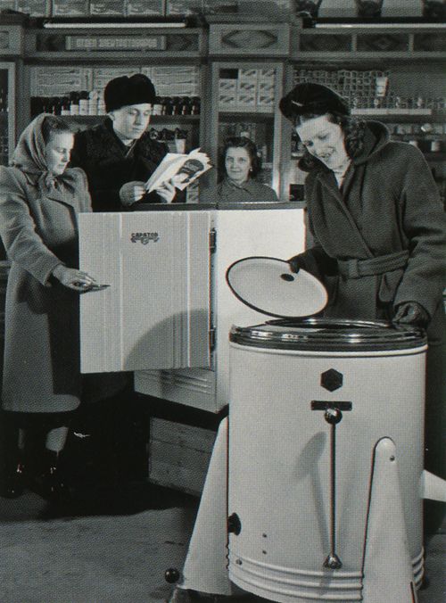 an old black and white photo of some people in a store looking at something on a machine