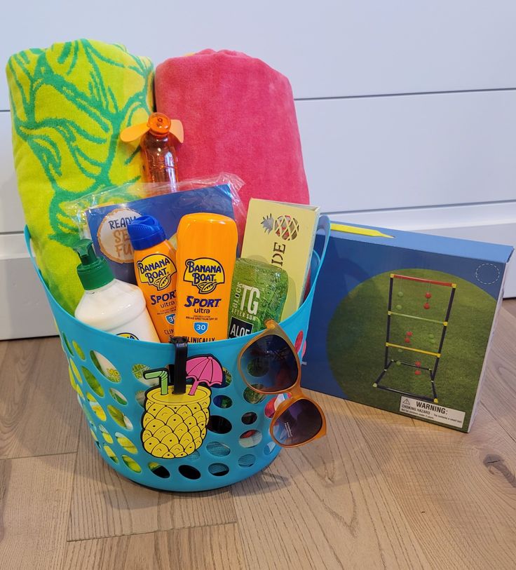 a blue basket filled with personal care items on top of a wooden floor next to a towel