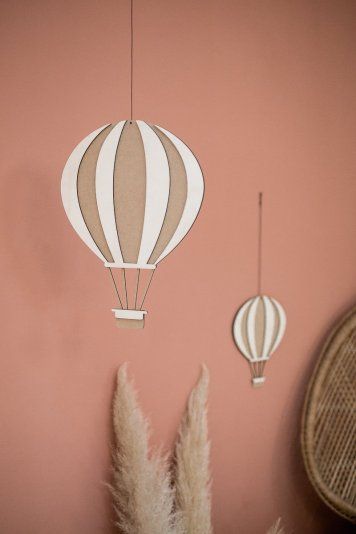 two hot air balloons are hanging from the wall next to some pamodia plants