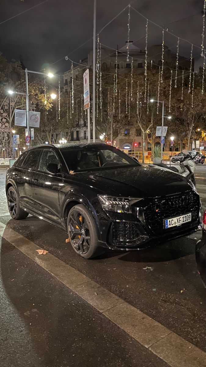 a black car is parked on the side of the road in front of some cars