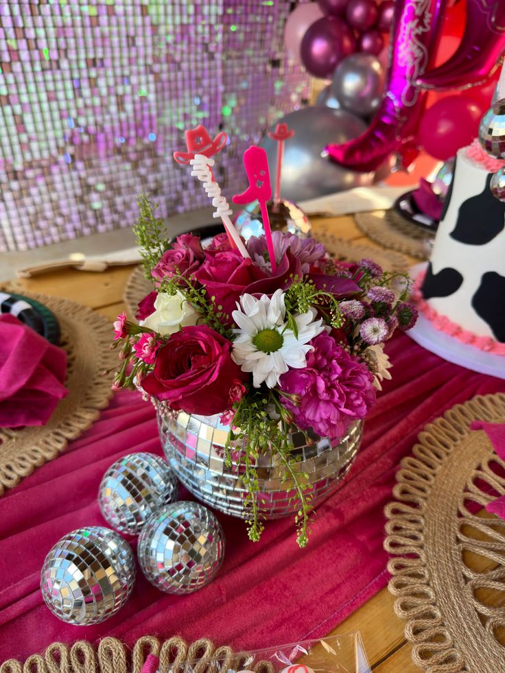 a vase filled with flowers on top of a table next to disco balls and other decorations