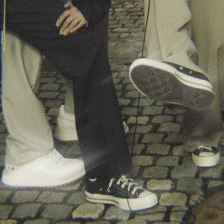 two people standing next to each other on a brick road with their feet in the air