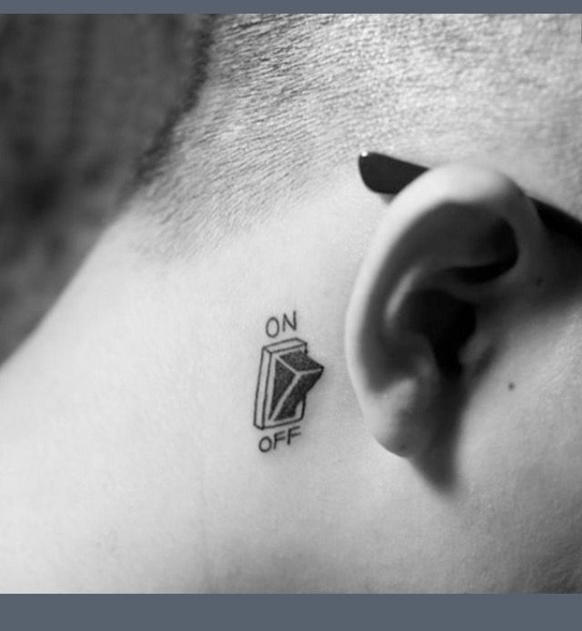 a black and white photo of a man's ear with an on off tattoo