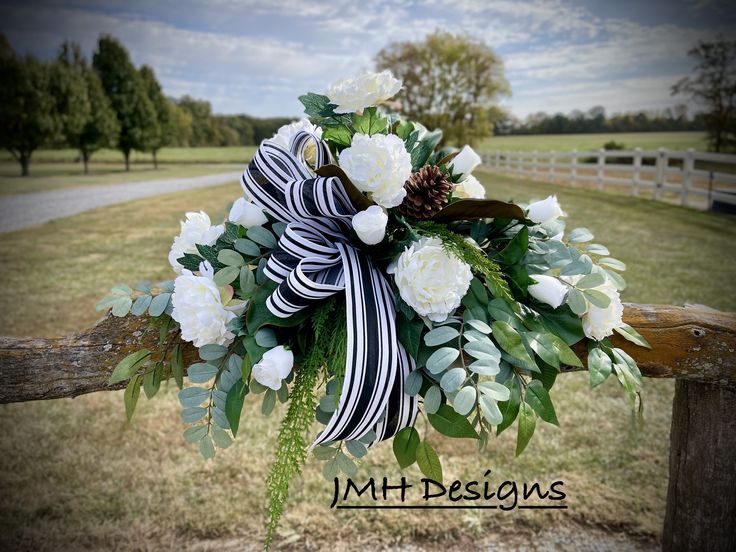 a bouquet of white flowers is tied to a wooden fence in front of a field