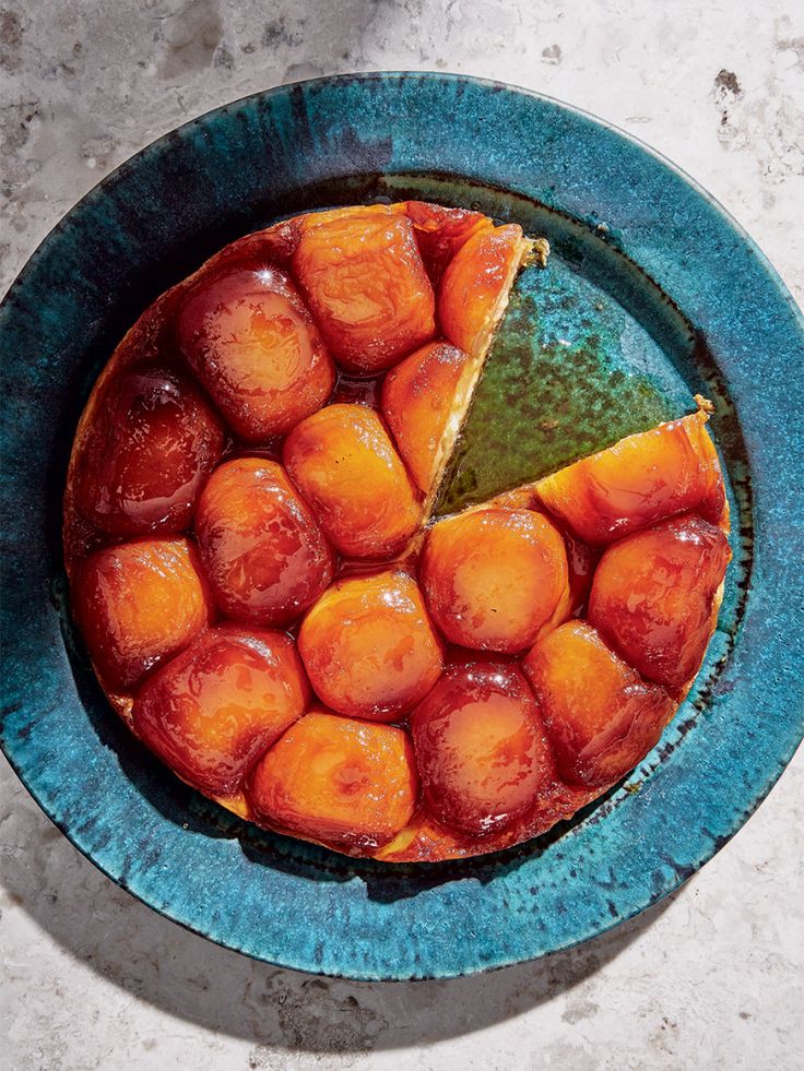 a blue plate topped with a pie covered in fruit