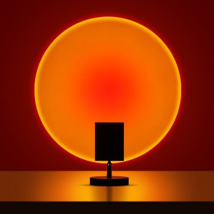 a lamp that is on top of a table in front of a red background with an orange circle