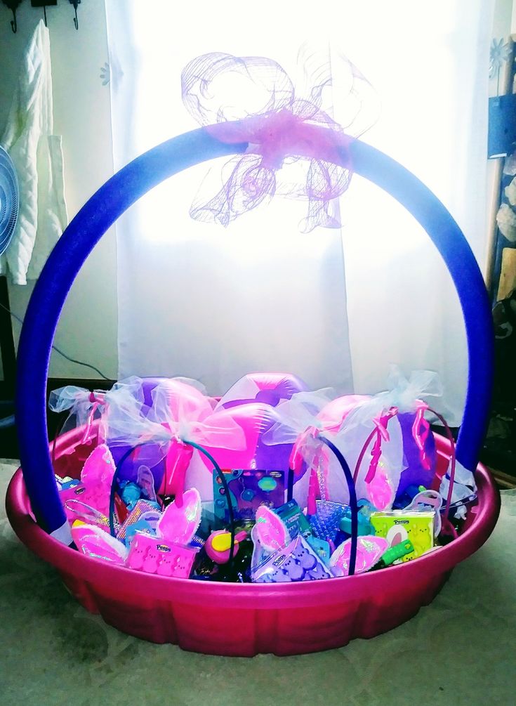 a pink basket filled with lots of candy in front of a white curtain and window