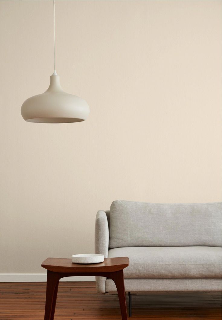 a living room with a couch, coffee table and lamp hanging from the ceiling over it