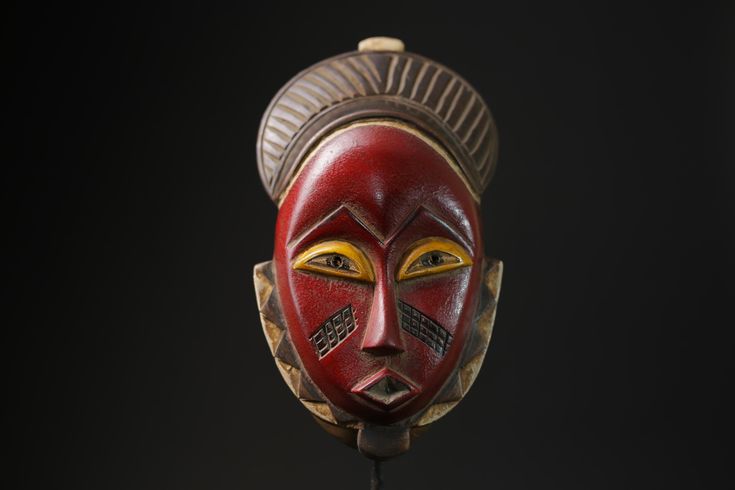 a red mask with yellow eyes on a black background