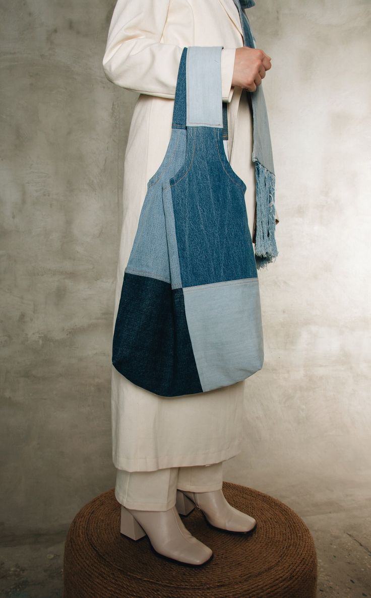 a woman in white coat holding a blue and grey bag on top of a round mat