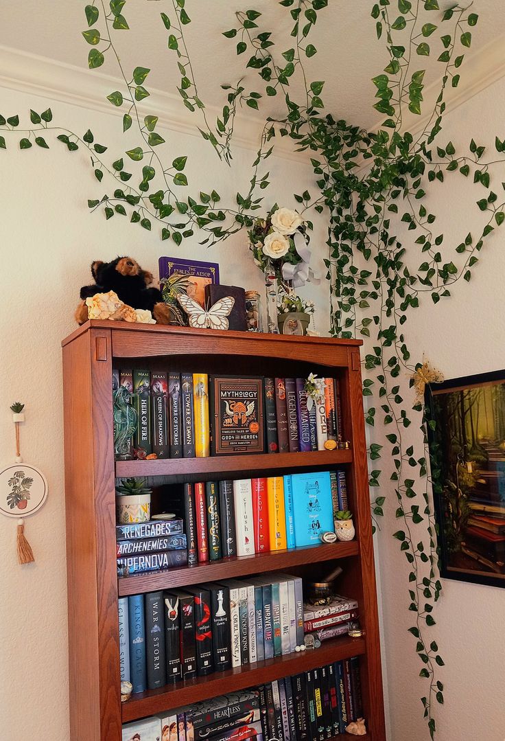 a bookshelf filled with lots of books next to a plant on the wall