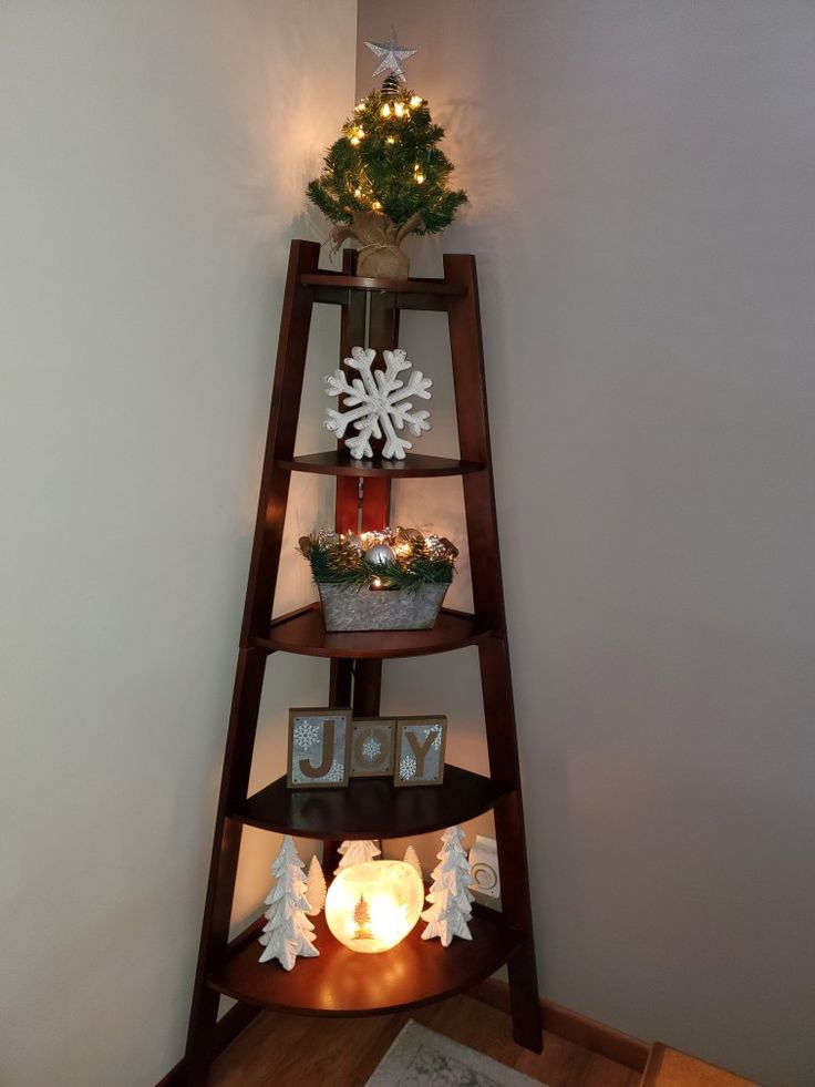 a wooden shelf with christmas decorations on top and lights in the corner next to it