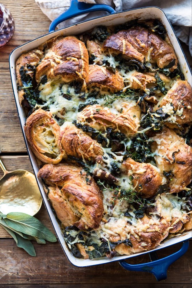 a casserole dish with spinach, cheese and bread in it on a wooden table