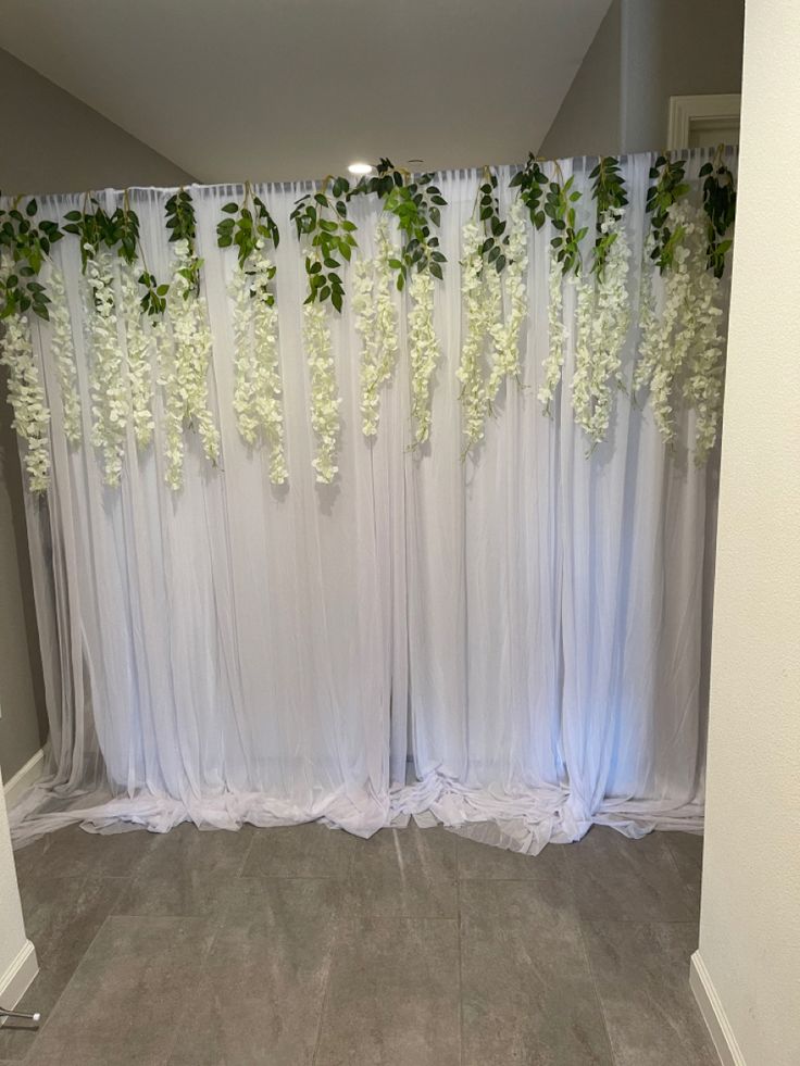 a room with white curtains and flowers on the wall