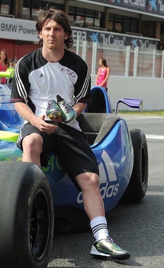 a man sitting on top of a blue race car in the middle of a street