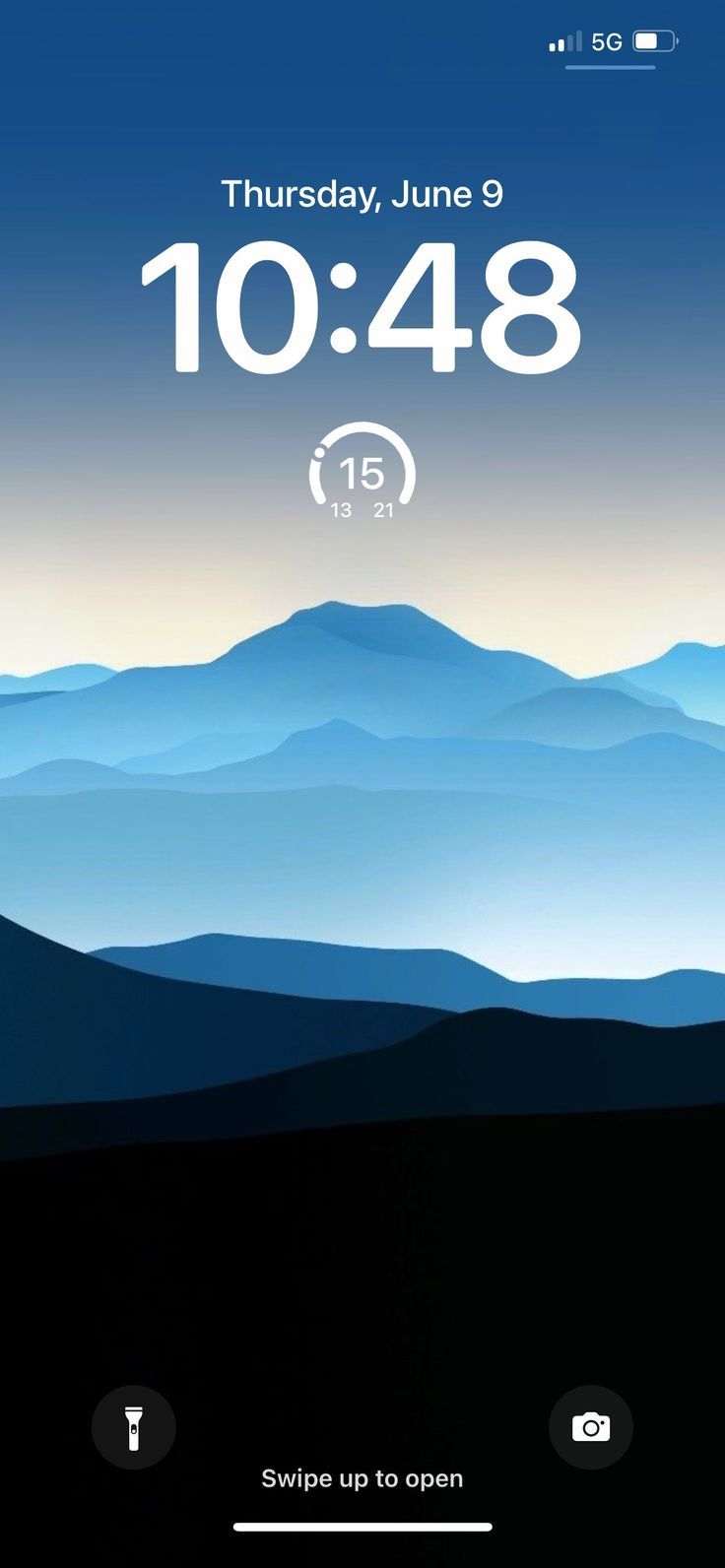 an iphone screen with the time displayed on it and mountains in the backgroud