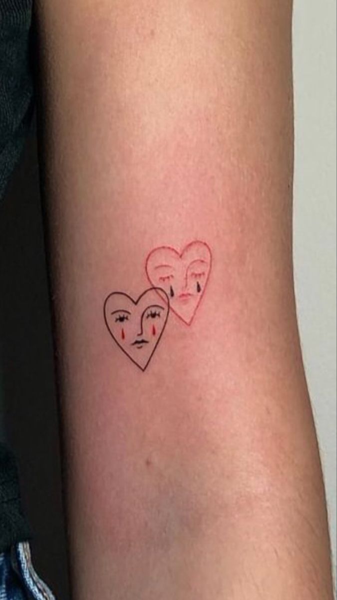 two hearts with faces drawn on the side of their arm and behind them is a woman's face