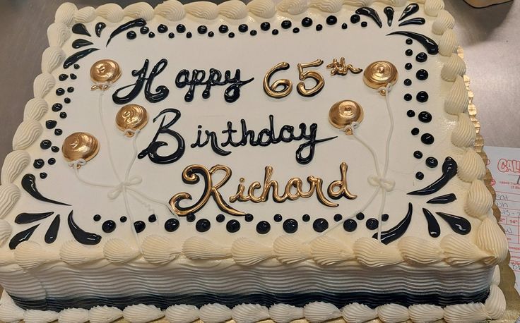 a white birthday cake with black and gold decorations