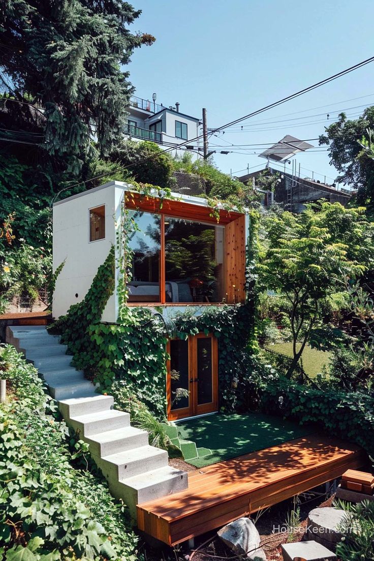 the house is surrounded by greenery and has stairs leading up to it's upper level