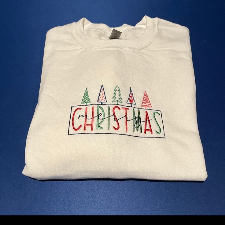 Merry Christmas Embroidered Unisex Sweatshirt. Gildan Heavy Blend. Available In White. Christmas White Embroidered Tops, Christmas Cotton Sweatshirt With Embroidered Logo, White Tops With Custom Embroidery For Christmas, White Top With Embroidered Logo For Christmas, White T-shirt With Embroidered Text For Winter, White Tops With Embroidered Logo For Christmas, White Cotton Christmas Sweatshirt, White Christmas Tops With Embroidered Graphics, White T-shirt With Embroidered Graphics For Winter